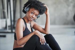 Focused photo. African american woman with curly hair and in sportive clothes have fitness day in the gym photo