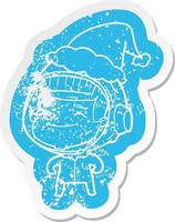 happy cartoon distressed sticker of a astronaut wearing santa hat vector