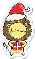 distressed sticker cartoon of a lion with christmas present wearing santa hat vector