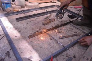 un trabajador soldando hierro para una mesa. soldadura eléctrica. soldadura manual. foto