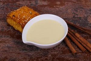 Condenced milk in the bowl with sinnamon and pastry photo