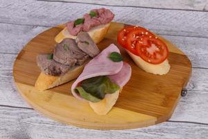 Bruschetta with tomato, ham and tongue photo