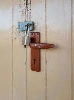 The silver padlock is locked on the wooden door. photo