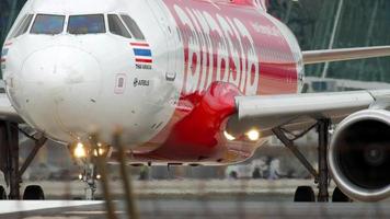 PHUKET, THAILAND   NOVEMBER 28, 2017 - AirAsia Airbus A320 HS ABY taxiing before departure from Phuket airport, and longtail fisher boat at background video