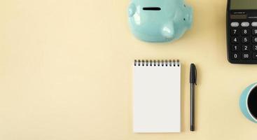 Planning concept with notepad, piggy bank, calculator and coffee. Banner of yellow pastel color with copy space. photo