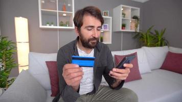 homem fazendo compras com cartão de crédito. o homem que paga o pedido que fez no telefone com um cartão de crédito. tirar um cartão de crédito do bolso. video