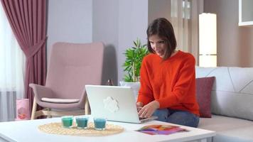 sorprendido en la computadora. mujer que se regocija. joven mujer atractiva en traje naranja trabajando en la computadora portátil. video