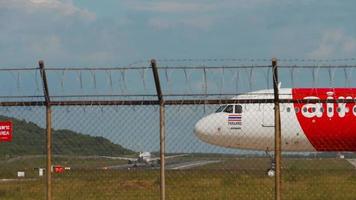 phuket, thailand 27 november 2019 - airasia airbus a320 flygplan väntar på starttillstånd, ett annat flygplan lyfter i bakgrunden. video