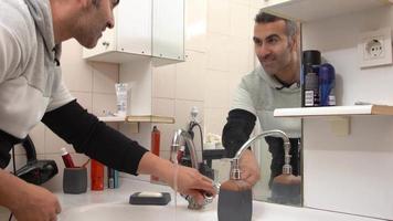 Happy man washing his face. Happy faces of the man washing his face in the bathroom in the morning. video