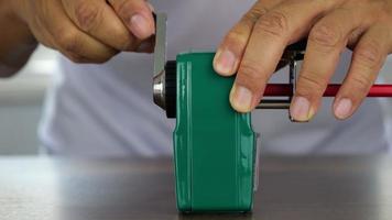 Slow motion male teacher's hand sharpening red pencil with green sharpener, education concept. video