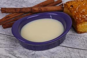 Condenced milk in the bowl with sinnamon and pastry photo