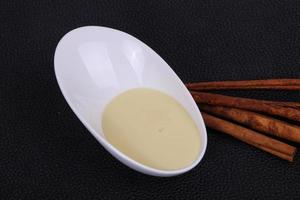 Condenced milk in the bowl with sinnamon and pastry photo