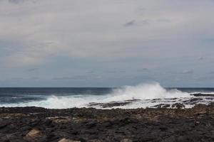 Turbulent ocean waves with white foam beat coastal stones photo