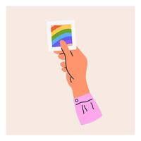 una mano sostiene una foto lgbt. mes del orgullo, bandera lgbt, arcoiris. ilustración vectorial plana vector
