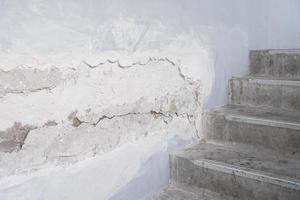 house broken. concrete crack. Water damage building interior. large crack white concrete wall photo