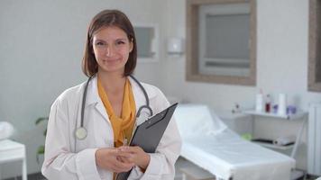 Ärztin lächelt in die Kamera. Ärztin im weißen Kittel lächelt in die Kamera im Krankenzimmer. video