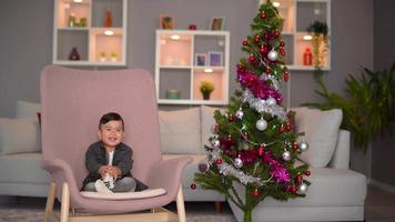 New year, baby and pine. Baby sitting near decorated pine tree and celebrating new year, cheerful and funny video