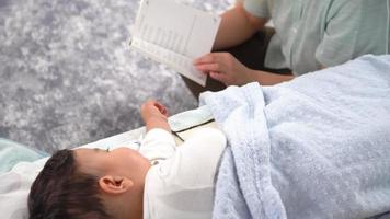mutter liest ihrem baby märchen vor. Die Mutter liest ihrem Baby ein Märchen vor und das Baby schläft ein. Die Mutter deckt die Decke zu und geht. video