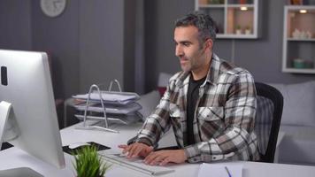 trabajador de oficina en casa feliz. hombre trabajando en casa felizmente trabajando en la computadora. video