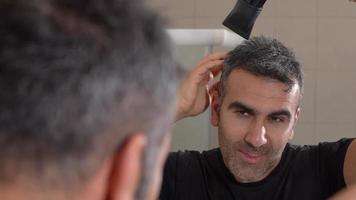 hombre con secador de pelo. el hombre en el baño se seca el pelo con un secador de pelo. video