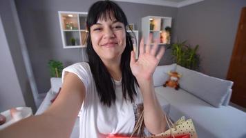 videochatten tijdens het winkelen. jonge mooie vrouw toont aan de telefoon de oranje outfit die ze heeft gekocht. mooie warme vriendelijke telefoon video-oproep. video