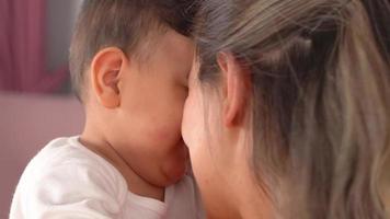 de moeder houdt van haar baby. moeder houdt van haar baby in close-up. ze leggen hun hoofd op hun hoofd en zijn gelukkig. dit is een slow motion-video. video