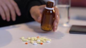 Brown medicine bottle being spilled on white table. video