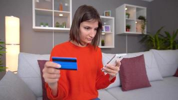 vrouw winkelt met een creditcard. vrouw betaalt haar bestelling aan de telefoon met een creditcard. een creditcard uit je zak halen. video