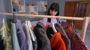 Choosing a dress from the wardrobe. Like casual clothes. Young beautiful brunette girl admires a beautiful dress from her wardrobe and goes to get dressed. video