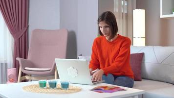 surpreso com o computador. mulher alegre. jovem mulher atraente com roupa laranja, trabalhando no laptop. video