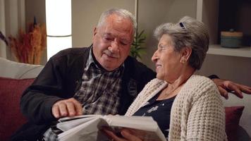 älteres paar emotionale momente. älterer ehemann und ehefrau, die sich ein fotoalbum ansehen. eine Familie sein, alt werden, in die Vergangenheit zurückkehren. glückliche Momente video