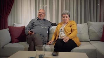 Old age and happy news. Elderly couple making a video call with their grandchildren on the phone. Grandfather and grandmother who are longing for their children.