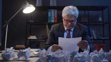 le directeur froisse les papiers. le gestionnaire travaillant à l'ordinateur examine les documents et les froisse. la table est pleine de papiers froissés. video