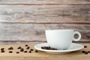 A white coffee cup with a saucer is placed on a wooden plate and on a wooden background. photo