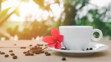 A white coffee cup with a saucer is placed on a wooden plate on the landscape nature background. photo