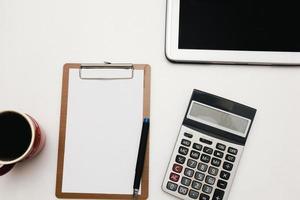 The top view of the office desk blank paper, pen, calculator, tablet. Financial planning and work concept. photo