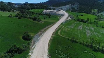 strada sterrata nella verde vallata, costruzione di strade. in costruzione, strada sterrata nel verde della vallata. video