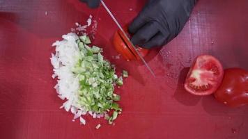 el cocinero está cortando el tomate. elaboración de ensaladas. el cocinero está cortando el tomate para usar en la ensalada. video