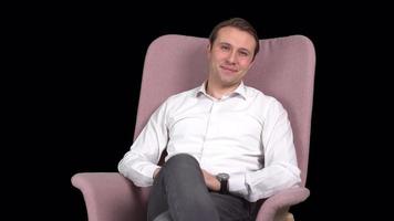 Smiling man looking at camera. The man sitting in the chair looks at the camera and laughs. Transparent background. video