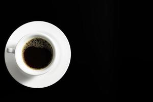 Black coffee in white coffee cup and saucer on black background. photo