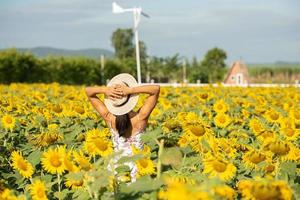 hermosa mujer joven en un campo de girasoles con un vestido blanco. viajar en el concepto de fin de semana. retrato de mujer auténtica con sombrero de paja. al aire libre en el campo de girasol. foto