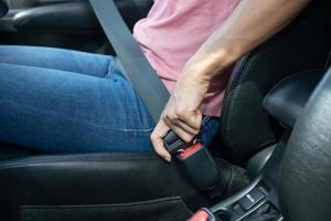 woman hand fastening a seatbelt in the car, Cropped image of a woman sitting in car and putting on her seat belt, Safe driving concept. photo