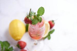 menta de limonada de limón y fresa fresca hecha en casa en vidrio, cóctel frío de verano, mojito de limón y fresa, fondo claro, espacio para copiar, un refrescante concepto de bebida de verano. foto