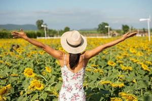 Beautiful young woman in a field of sunflowers in a white dress. travel on the weekend concept. portrait of authentic woman in straw hat . Outdoors on the sunflower field. photo