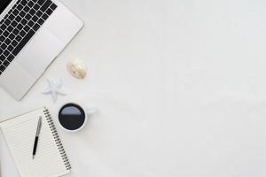 Flat lay photo of office desk with laptop, notebook, pen, coffee, starfish and shells with copy space background