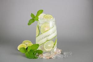 summer refreshing drinks, homemade lemonade made from lime, lemon, cucumber and  mint with ice in glass on an old concrete background. selective focus. photo