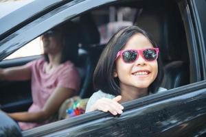 vacaciones familiares, familia feliz en un viaje por carretera en su auto, mamá manejando auto mientras su hija sentada al lado, mamá e hija viajan. paseo de verano en automóvil. foto