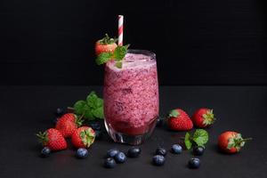 Delicious strawberry, mulberry and blueberry smoothie garnished with fresh berries and mint in glass. soft focus. beautiful appetizer pink raspberries, well being and weight loss concept.