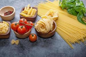Mixed dried pasta selection on wooden background. composition of healthy food ingredients isolated on black stone background, top view, Flat lay photo