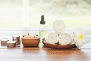 Sea salt, towels, aroma oil in bottles and flowers on vintage wooden background. Selective focus. photo